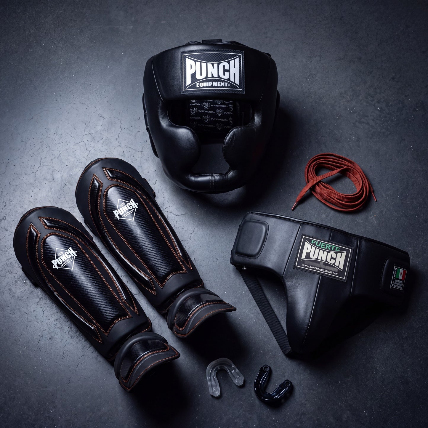Punch Equipment women's Pro Protective Kit — Trophy Getters full-face head gear, Black Diamond Precision Plus carbon shin pads with orange stitching, Mexican Fuerte ladies groin guard with rust-red rear lace, and two gel mouthguards on dark concrete